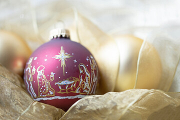 an original religious themed photograph of a burgundy christmas ornament with the nativity scene wit