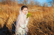 © Arsentyev Vladimir - a girl in a field in the fall holds yellow wildflowers, turned sideways, looks into the camera. Dressed in casual clothes, sweater, scarf