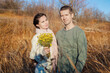© Arsentyev Vladimir - An adult couple in love, hugging in a field, in the fall with yellow wildflowers, he looks into the camera. Dressed in casual clothes, sweater, scarf