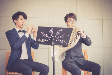 Young musician team playing trumpet and horn in music room.