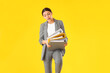 Surprised teenage girl with folders on yellow background
