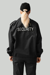 Wall Mural - Female security guard on grey background, back view