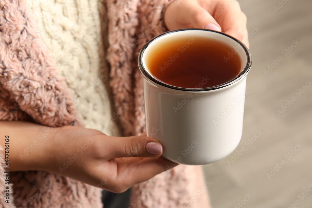 Woman drinking tasty tea indoors, closeup