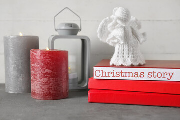 Wall Mural - Books with angel toy and glowing candles on table. Christmas story