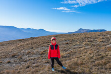 Boy 8 Years Old In A Red Jacket On The Top Of A Mountain After A Long Climb During A Hike