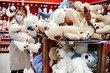 © Татьяна Волкова - Beautiful woman in coat stands next to huge box of stuffed toys and holds large polar bear in her hands. Children's toy store. Shopping during pandemic. Protective equipment.
