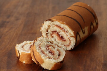 Wall Mural - Sponge cake roll with strawberry filling on a wooden background. Dessert, biscuit roll. 