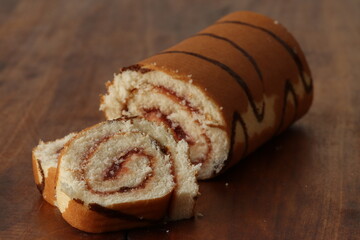 Wall Mural - Sponge cake roll with strawberry filling on a wooden background. Dessert, biscuit roll. 