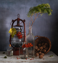 Still Life With Glass Bottles, Bunches Of Mountain Ash, A Kerosene Lamp And Spilled Nuts