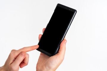 Poster - Hands with phone close-up. Girl points her finger at smartphone screen. Women's hands with switched off mobile gadget. Black phone for application demonstration. Cellphone on light background