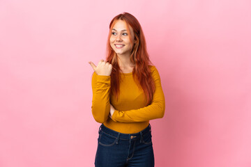 Wall Mural - Teenager Russian girl isolated on pink background pointing to the side to present a product