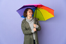 English Woman Holding An Umbrella Isolated On Purple Background Looking Side
