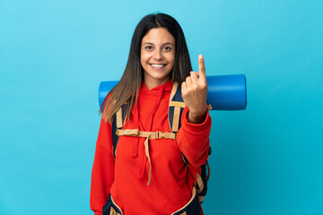 Wall Mural - Young mountaineer woman with backpack doing coming gesture