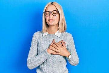 Poster - Beautiful blonde woman wearing glasses smiling with hands on chest with closed eyes and grateful gesture on face. health concept.