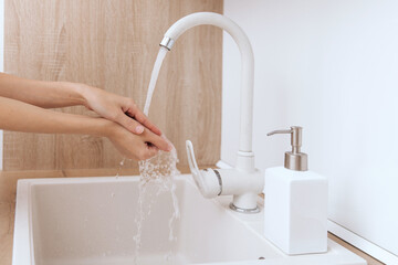 Wall Mural - Washing hands under the flowing water tap. Hygiene concept hand detail. Washing hands rubbing with soap for corona virus prevention, hygiene to stop spreading corona virus in or public wash room.