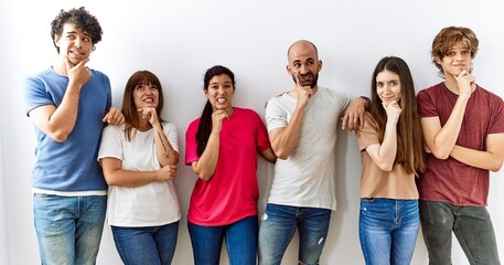 Group of young friends standing together over isolated background thinking worried about a question, concerned and nervous with hand on chin