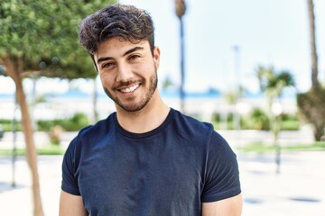 Young hispanic man smiling happy standing at the city.