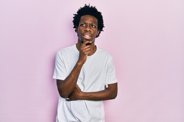 Poster - Young african american man wearing casual white t shirt with hand on chin thinking about question, pensive expression. smiling with thoughtful face. doubt concept.