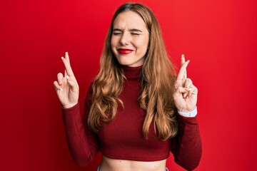 Sticker - Young blonde woman wearing turtleneck sweater gesturing finger crossed smiling with hope and eyes closed. luck and superstitious concept.