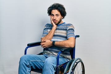 Sticker - Handsome hispanic man sitting on wheelchair thinking looking tired and bored with depression problems with crossed arms.