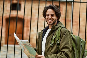 Handsome hispanic man looking at travel map at the city