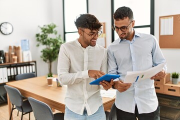 Canvas Print - Two hispanic men business workers using touchpad reading documents working at office