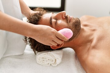 Poster - Young hispanic man having facial treatment at beauty center