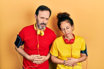 Sticker - Middle age couple of hispanic woman and man wearing sportswear and arm band with hand on stomach because indigestion, painful illness feeling unwell. ache concept.