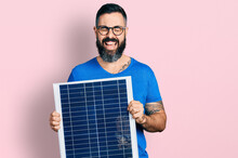 Hispanic Man With Beard Holding Photovoltaic Solar Panel Smiling And Laughing Hard Out Loud Because Funny Crazy Joke.