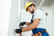 © Kostiantyn - Male worker professional electrician in uniform installing electrical outlet in apartment after renovation work
