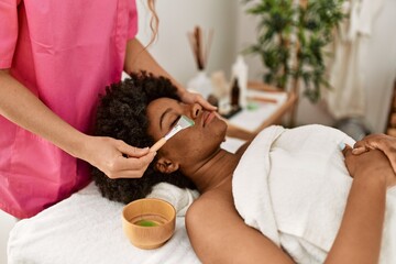 Sticker - Young african american woman having facial treatment at beauty center