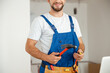 © Kostiantyn - Cropped shot of professional handyman worker in uniform smiling at camera and holding hammer during renovation work indoors