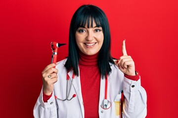 Sticker - Young hispanic doctor woman holding medical model smiling with an idea or question pointing finger with happy face, number one