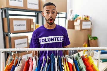 Poster - African american man wearing volunteer t shirt at donations stand afraid and shocked with surprise expression, fear and excited face.