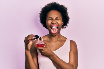 Poster - Young african american woman holding perfume angry and mad screaming frustrated and furious, shouting with anger looking up.