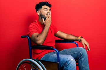 Canvas Print - Arab man with beard sitting on wheelchair bored yawning tired covering mouth with hand. restless and sleepiness.