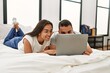 © Krakenimages.com - Young latin couple smiling happy using laptop at bedroom
