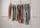Rack with stylish women's clothes near light wall