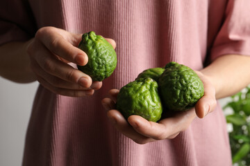 Woman holding fresh ripe bergamot fruits, closeup