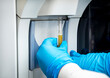 © F Armstrong Photo - Close up of gloved hands holding a samples of plasma under lab equipemnt