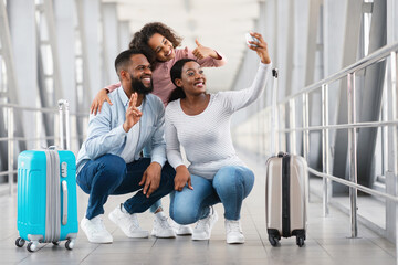 Wall Mural - Black family of three traveling, taking selfie in airport