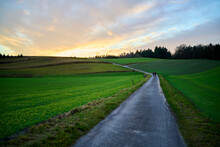 Road Between Fields In A Rural Area. With A Yellow And Blue Sunset. High-Danamic-Range (HDR)