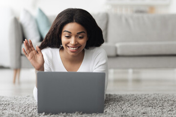 Wall Mural - Online chat. Smiling african american lady with laptop making video call, waving hand to webcam, resting at home