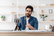 © Prostock-studio - Video recording for modern blog as a remote work. Arab guy in glasses talking to smartphone camera on tripod