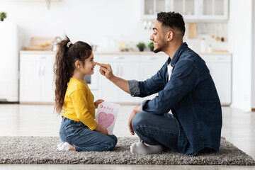 Wall Mural - Father's Day. Little Arab Girl And Dad Sitting On Floor In Kitchen