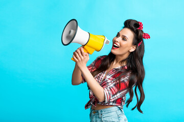 Wall Mural - Sexy pin up woman shouting into megaphone, advertising something, making announcement on blue studio background