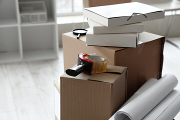 Cardboard boxes with belongings and packing tape in office on moving day