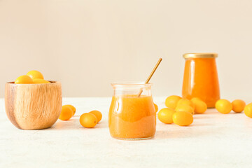 Wall Mural - Jar of tasty kumquat jam and fresh fruits on light background