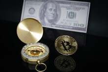 A Bitcoin Coin Lies Next To A Compass And A Hundred Dollar Bill