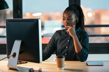 Wall Mural - Smart business woman working with computer while talking with earphone sitting in modern startup office.